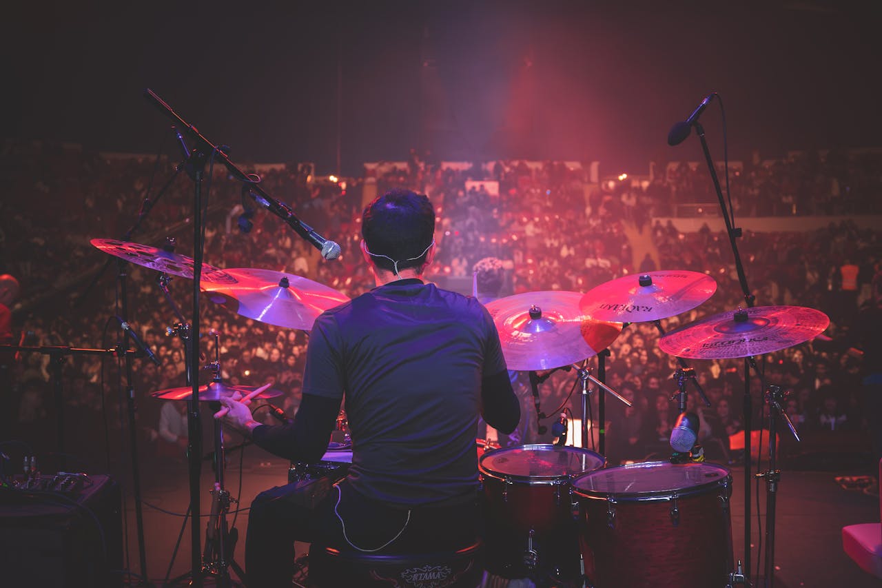 The Art of Drawing Readers In: Your attractive post title goes here Back view of drummer playing on stage at a live music concert with a packed audience.